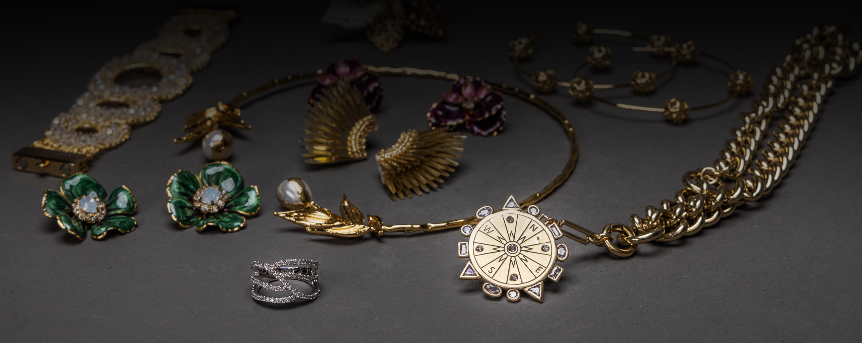 A sample of fashion jewelry carried by The Roguery with a compass necklace in the foreground.
